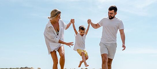 Happy Family Enjoys A Fun Walk Along The Sea