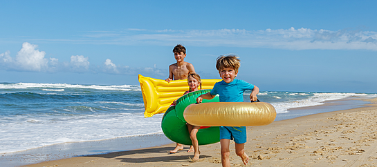Three Children Are Running Happily Along The Beach