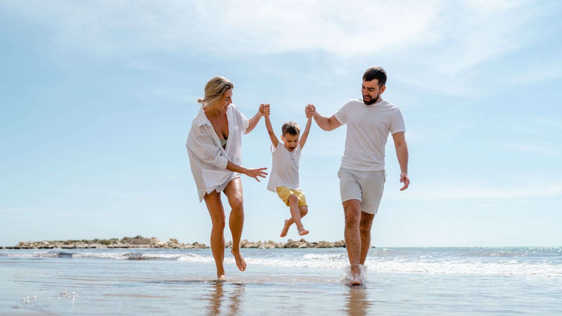 Happy Family Enjoys A Fun Walk Along The Sea