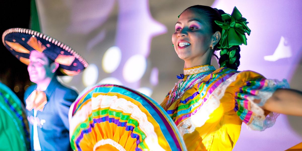 Group of cheerful artists performing Mexican folk dance