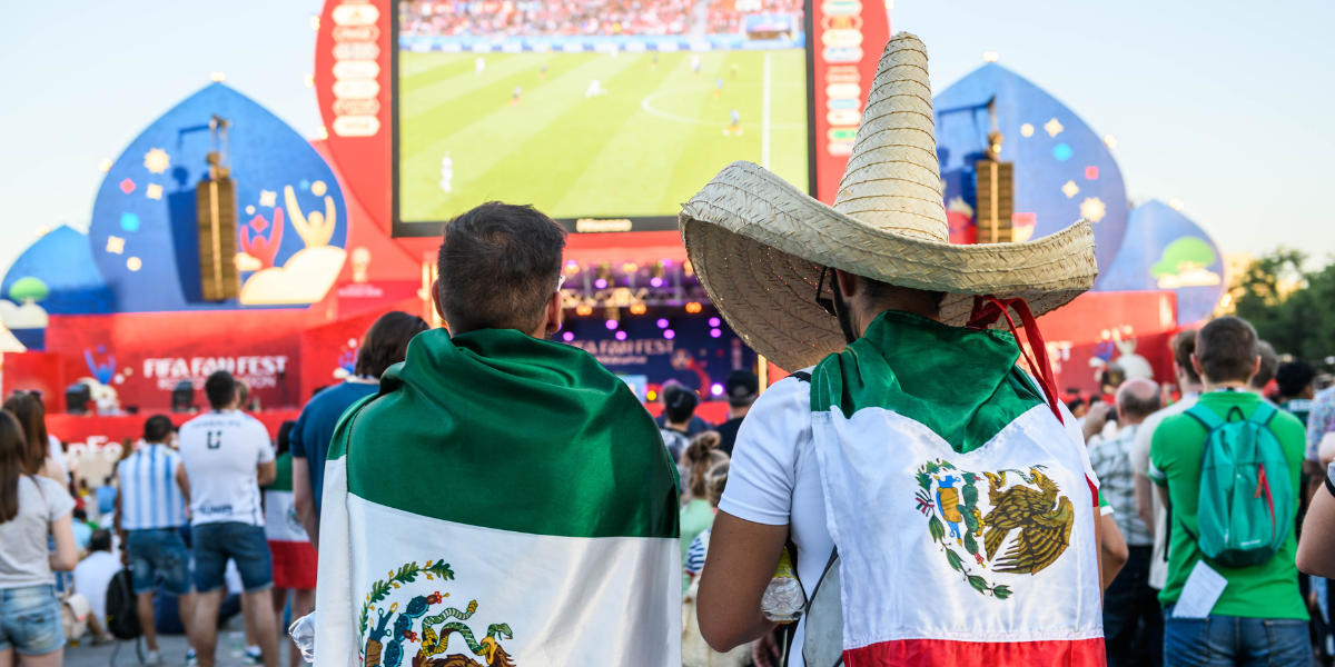 Fans with Mexican flags and traditional charro hats watching a match at the FIFA Fan Fest.