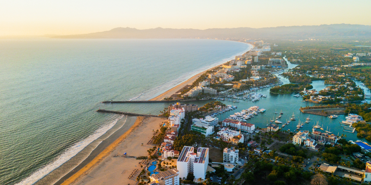 Vista aérea de Marina Vallarta al atardecer, mostrando Yates, resorts de lujo y costa del Pacífico