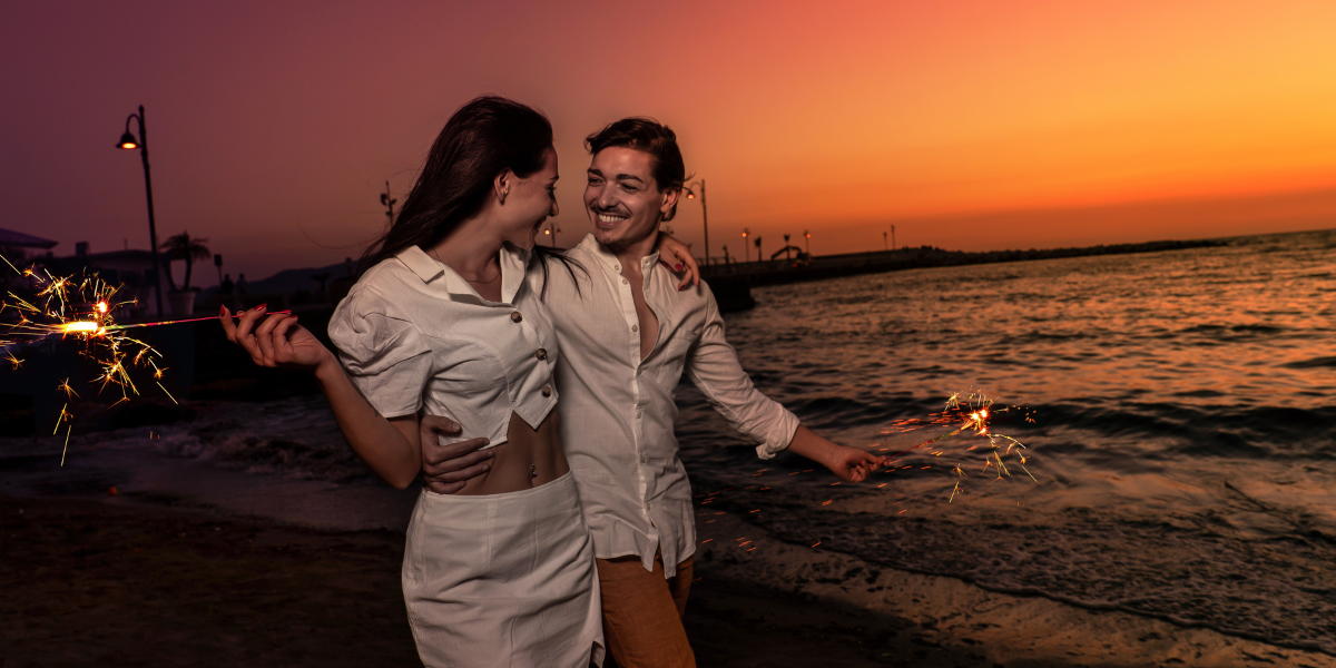 Pareja de novios felices al atardecer en La Playa con luces de bengala