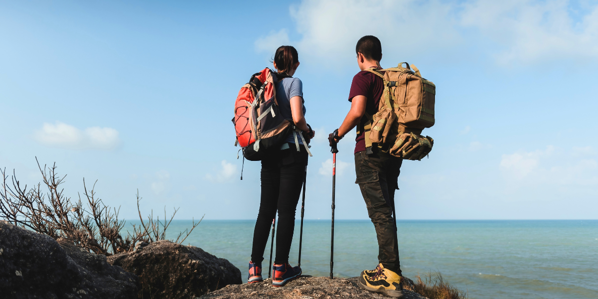 Joven pareja practicando hiking juntos con vista al mar