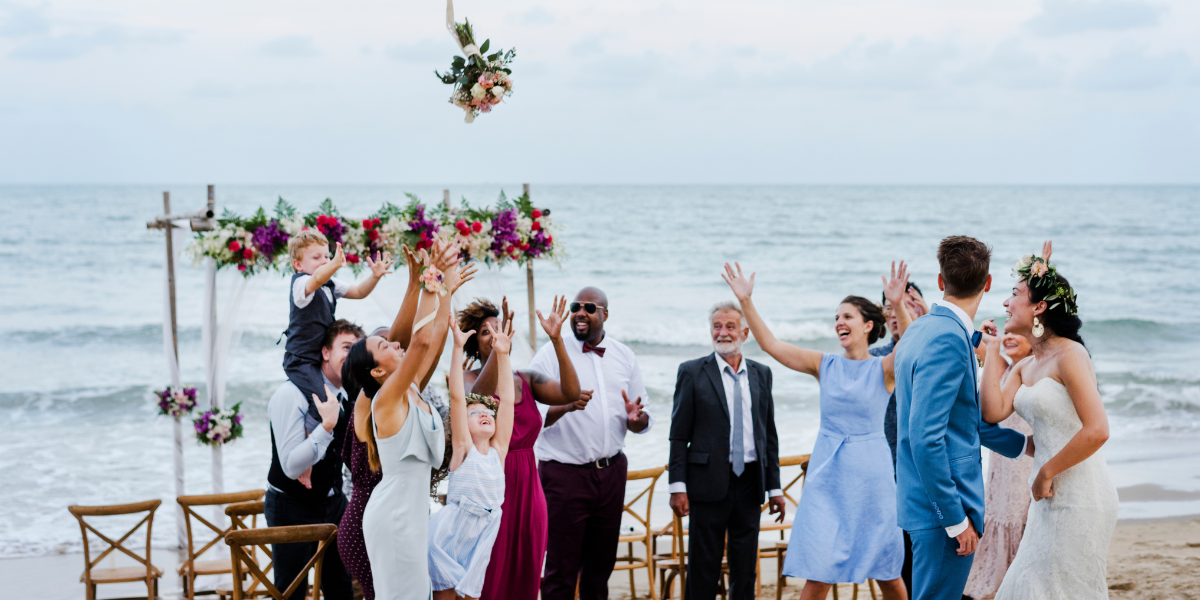 Invitados de bodas capturando el ramo de novia en la playa