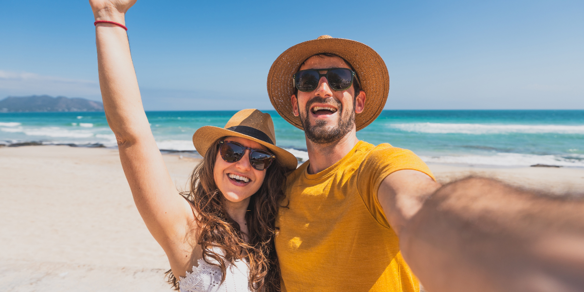 Couple taking a selfie with the beach in the background